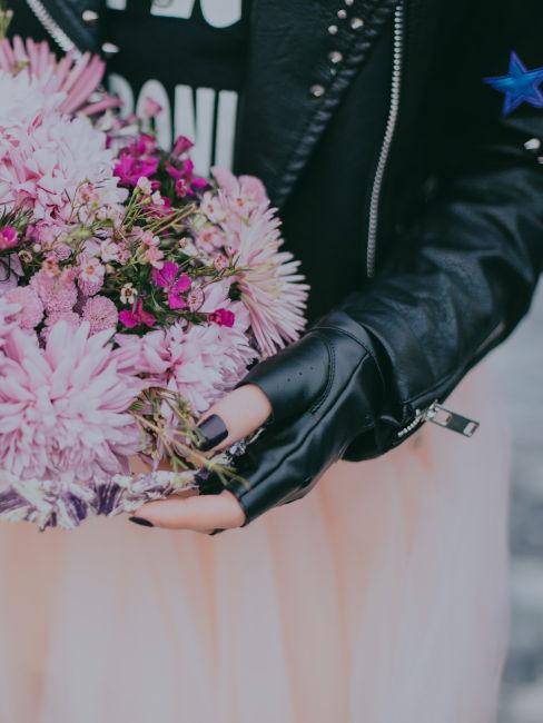 ragazza con giacca di pelle nera e bouquet viola