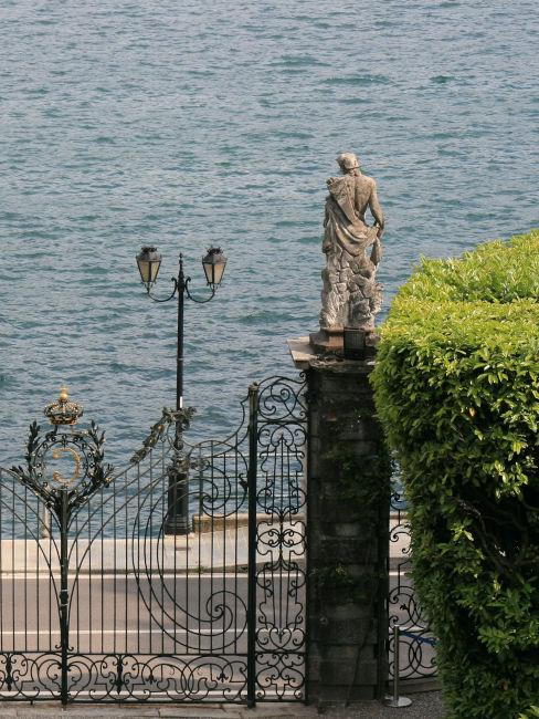 cancello in ferro batturo con statue sul lago