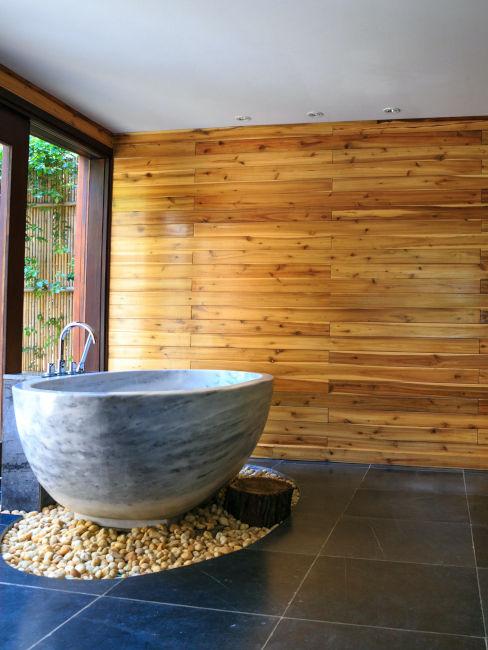 vasca in pietra in bagno con pareti in legno