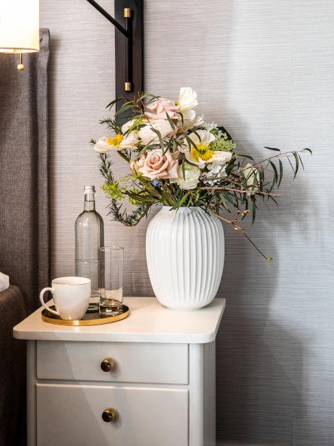 comodino in legno bianco con vaso e fiori