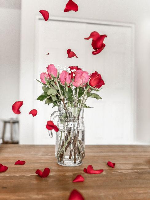 Vaso di rose con petali sul tavolo