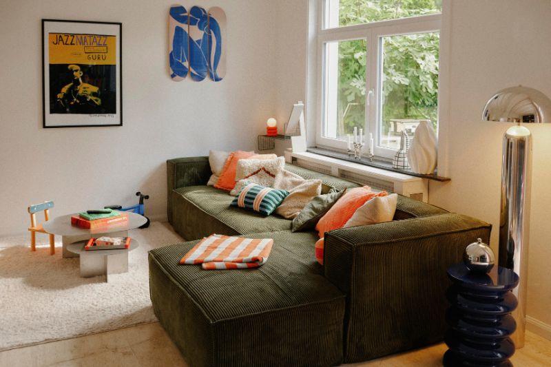 soggiorno con divano verde e accessori colorati