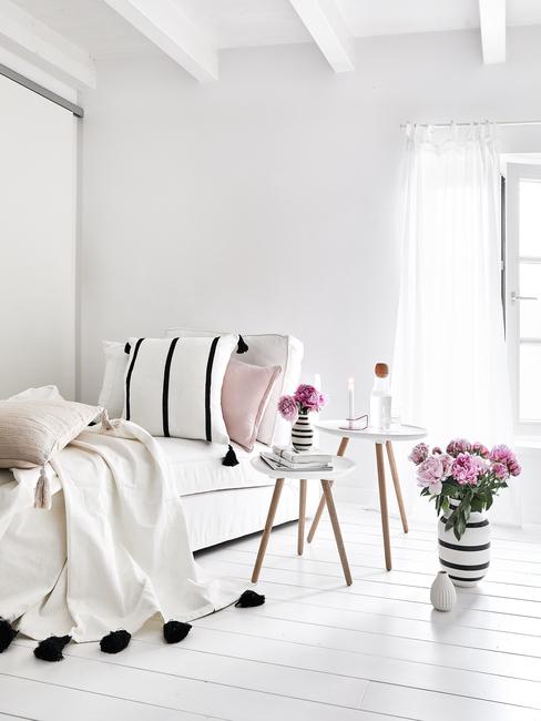 Witte woonkamer met witte belinnen en houten nachtkastje met bloemen baas