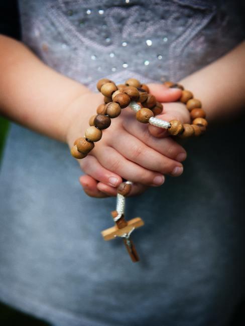 Meisje met een houten rozenkrans in haar hand.