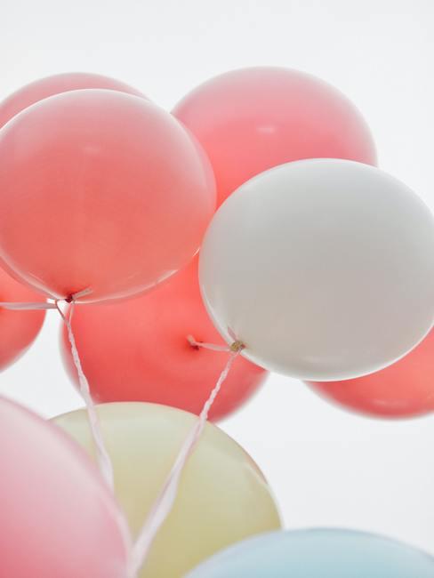 Perzik en witte ballonnen als decoratie op een communiefeest.