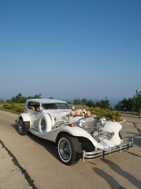 Witte trouwauto met trouwaccessoires en bloemen