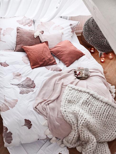 Zachte plaid op roze bedlinnen in witte slaapkamer