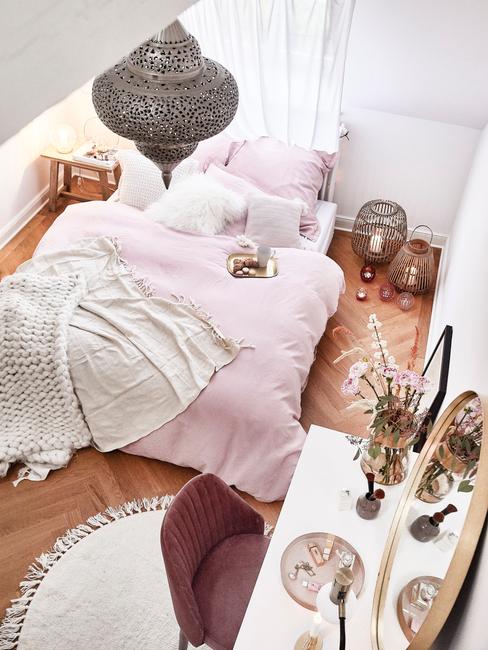 Zachte plaid op roze bedlinnen in witte slaapkamer