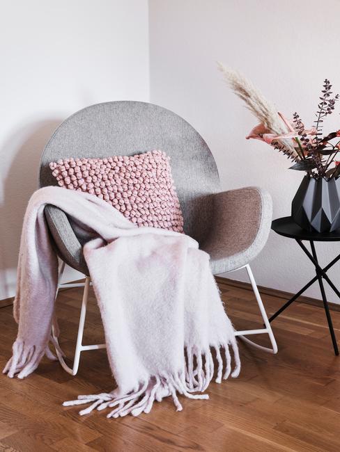 Zachte plaid op fauteuil met roze sierkussen