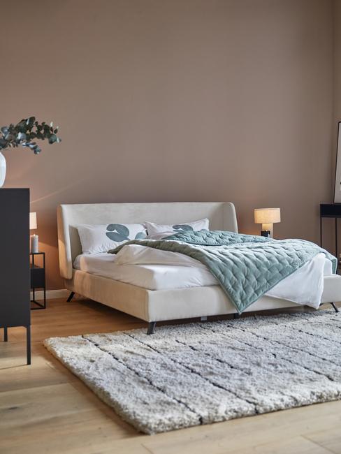 Slaapkamer met taupe muur en wit fluwelen bed