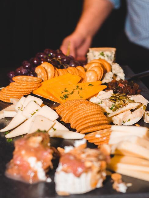 Kaasplank met diverse kazen en olijven, tomaten en andere snacks