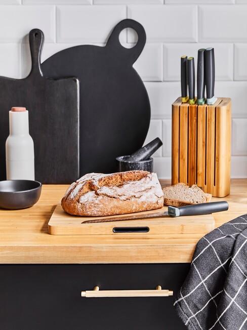 leisteen borden, brood en messen op een houten aanrecht