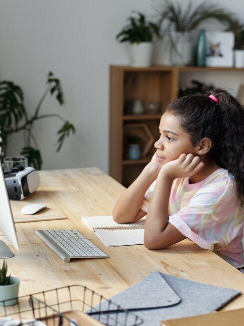 Meisje volgt afstandsonderwijs aan houten bureau in een meisjes slaapkamer
