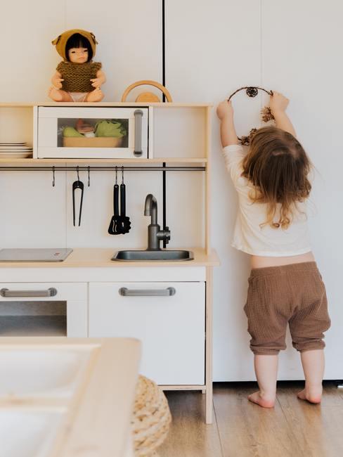 Een meisje speelt in een houten mini-keuken voor kinderen