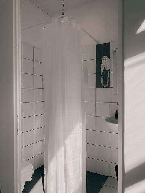 Witte badkamer met vierkante tegels met een wit douchegordijn