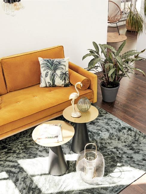 Zitbank in geel naast bijzettafels met houten blad