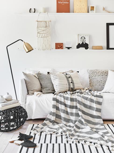 Woonkamer in wit met zitbank in creme en sierkussens naast een fluwelen fauteuil in lichtblauw