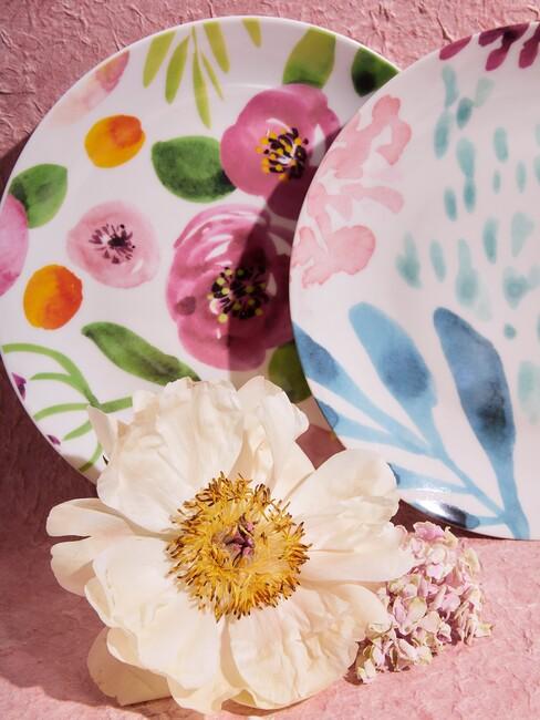 vrolijk gekleurd servies en een bloem met roze achtergrond