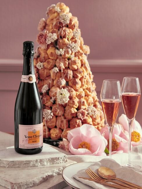 een toren van gebakjes met een fles rosé en champagne glazen