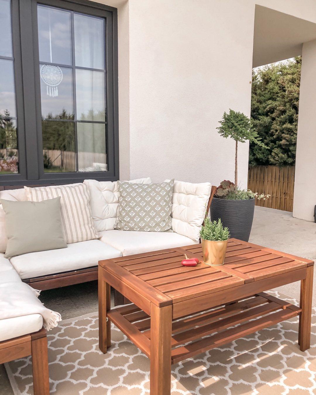 Outdoor loungeset met houten tafel voor een witte buitenmuur