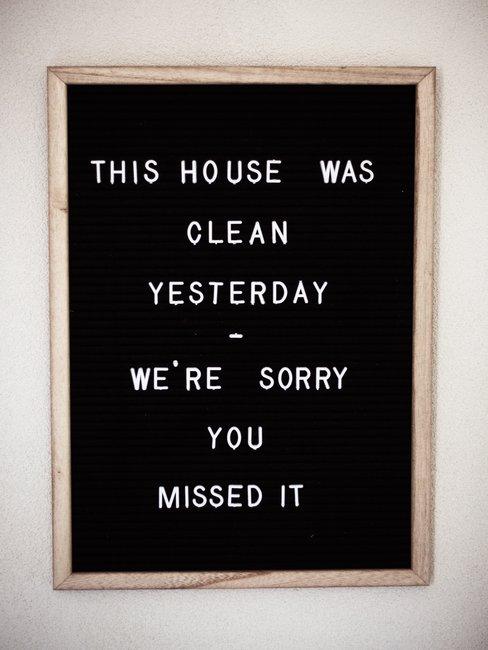 Zwart letterbord met witte letters en houten rand op witte muur voorjaarsschoonmaak