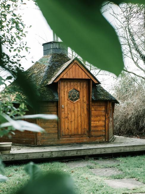 Zes hoekig houten huis met schoorsteen en voordeur op houten verhoging in de natuur
