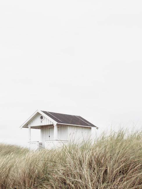 Wit houten huis in de duinen met grijze lucht