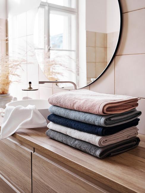 badkamer met een houten meubel en gekleurde handdoeken
