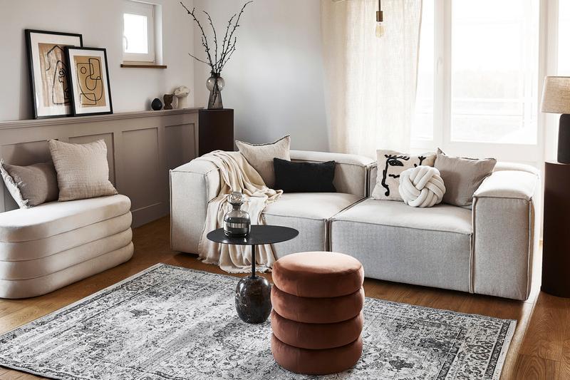 woonkamer met witte bank met vloerkleed en kussens en plaid