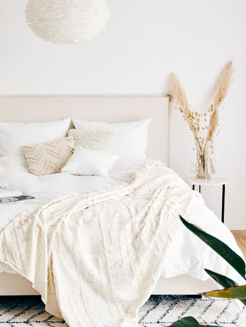 beige boxspring met wit dekbed met droogbloemen