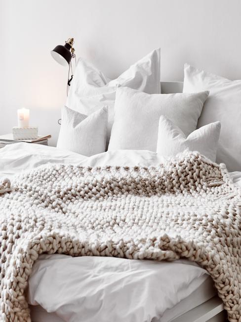 witte dekbed met een beige plaid en een zwarte wandlamp
