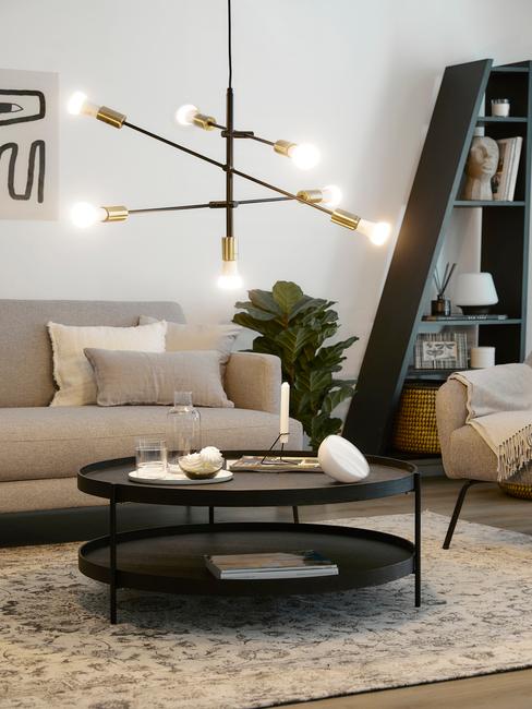 toupe bank met zwarte ronde bijzettafel en gouden hanglamp