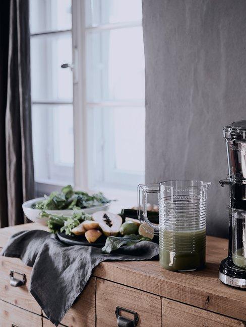Groene detox groentenshake op houten tafel met raam en gordijnen op de achtergrond