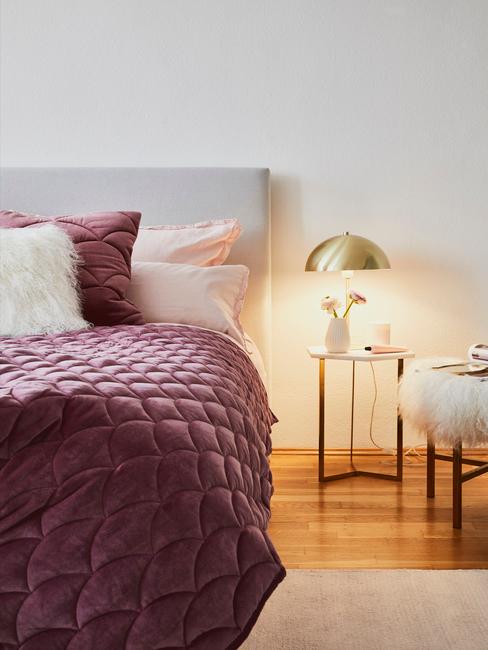 Indigo plaid met een Indigo kussen op een beige bed en een gouden lamp