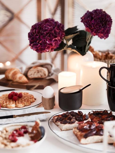 Indigo bloemen met witte kaarsen en zwart servies
