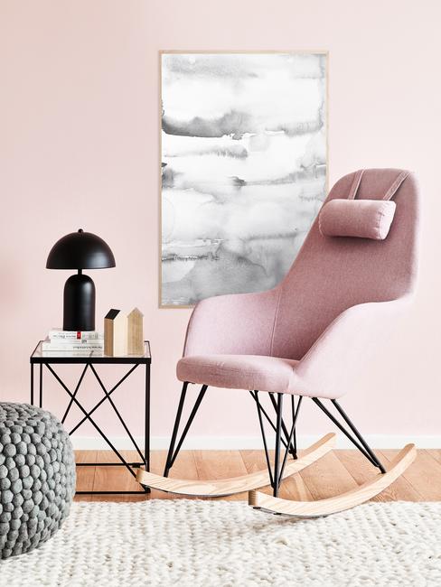 Schilderij Ophangen op een roze muur met een roze schommelstoel ervoor