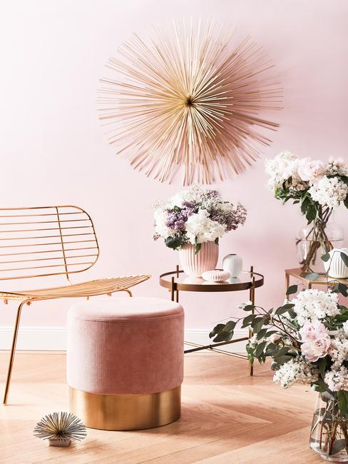 gouden wanddecoratie met een gouden stoel en een roze poef