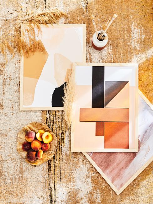 gele muur met houten lijsten en printen