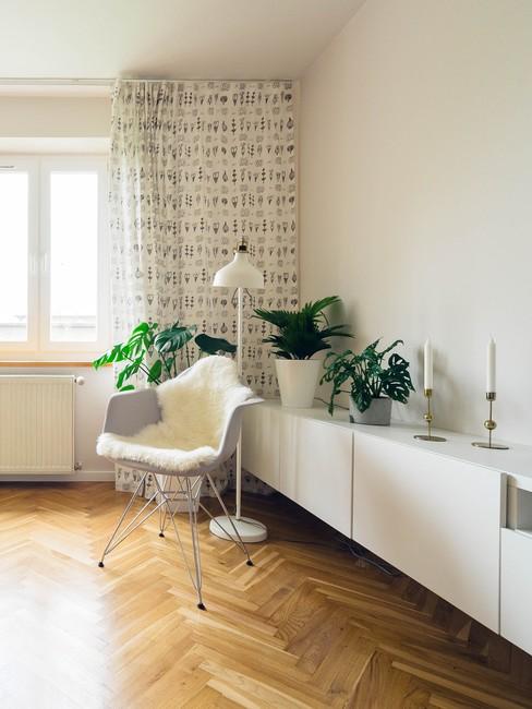 houten visgraatvloer met een witte wandkast en grijze stoel