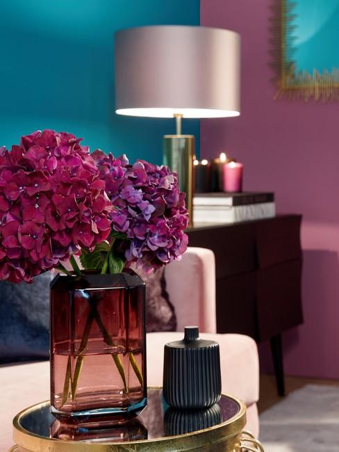 Decoratie van gedroogde bloemen in transparante vaas op een gouden tafel met een glanzend blad in een eclectische stijl.