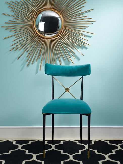 Een stoel met een decoratieve gouden spiegel aan de muur in een eclectische stijl