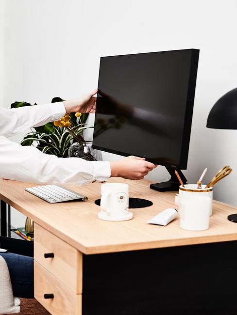 houten bureau met een zwart beeldscherm en witte pennenhouder