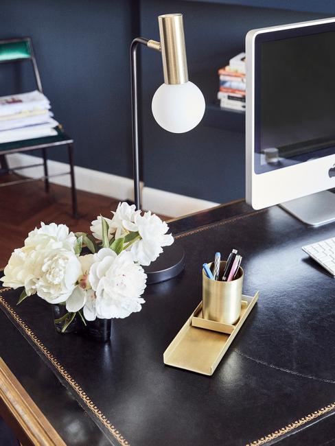 zwart bureau met gouden lamp en witte bloemen