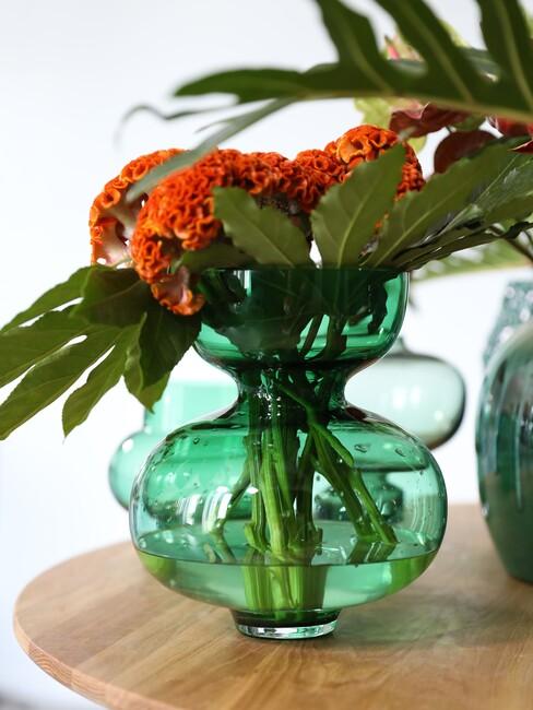 vaas in smaragdgoen met oranje bloemen