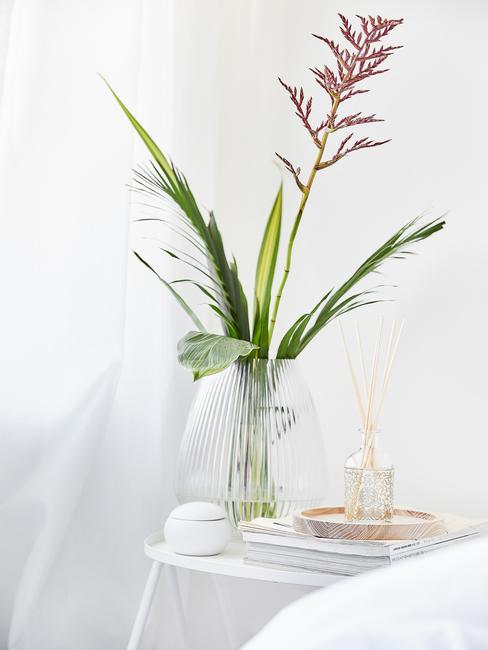 glazen vaas met een bloem op een witte tafel