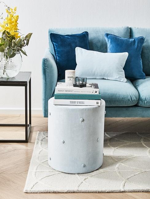 Lichtblauwe bank met poef op houten vloer met beige tapijt