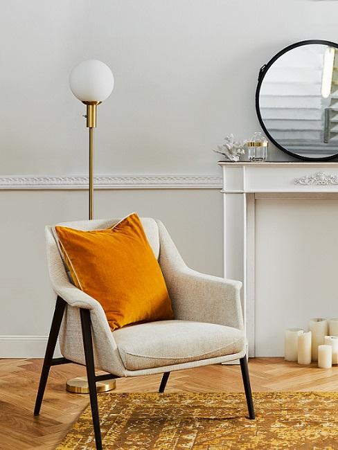 beige stoel met zwarte poef en oranje kussen