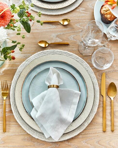 blauw servies met witte servetten en gouden servetringen