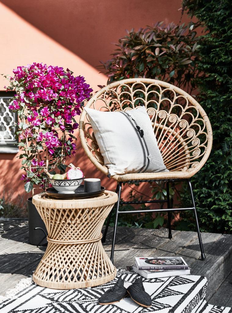 Zalm roze muur met rotan loungestoel en rotan bijzettafel op houten vlonder
