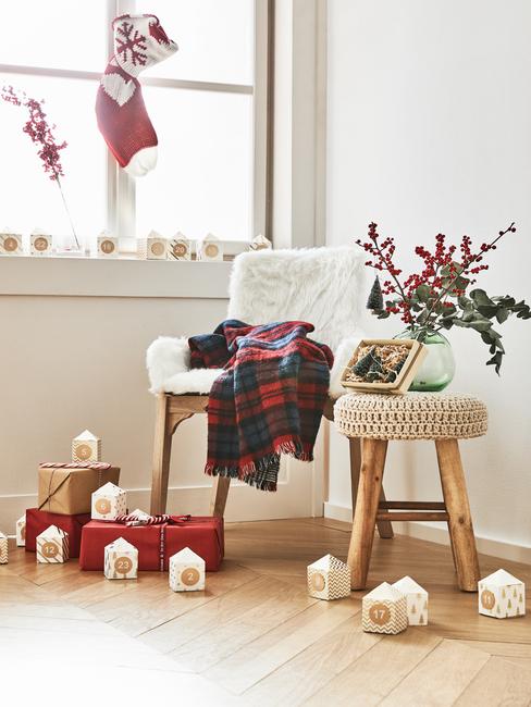Fauteuil bekleed met witte schapenvacht en houten kruk met bloemen in vaas en waxinelichten op de vloer